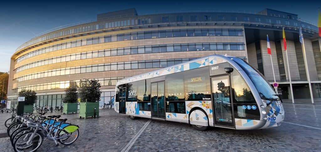 Tramway moderne devant un bâtiment en verre à Paris.