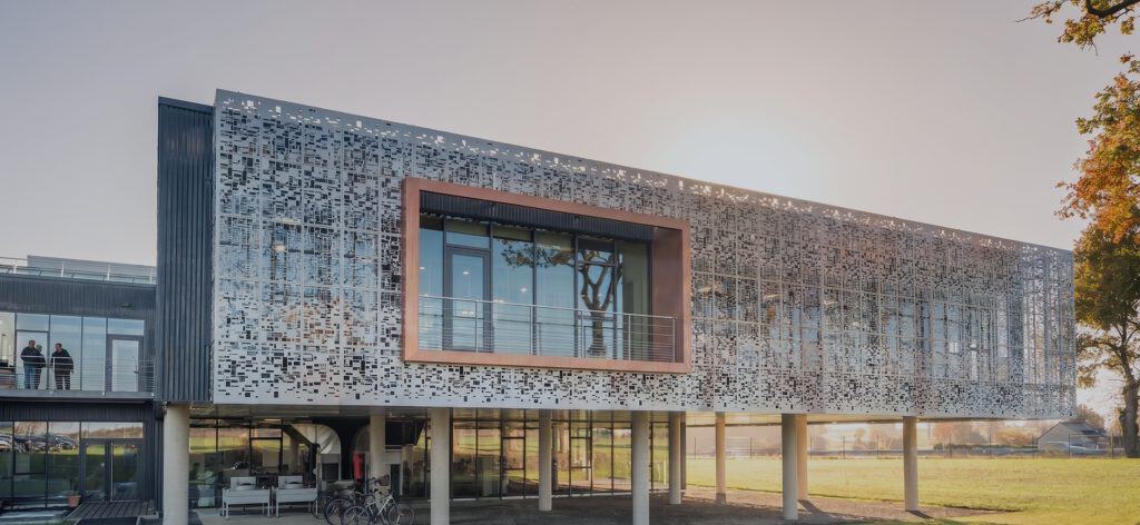Architecture contemporaine avec façade en métal perforé et grandes fenêtres.